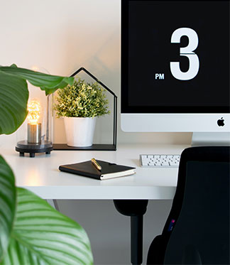cropped image of desk with computer, pot plants and notebook