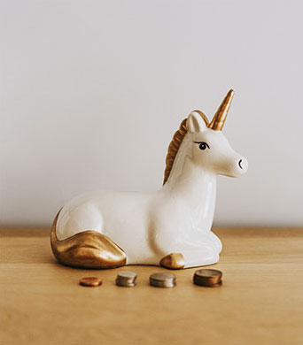 a small white ceramic unicorn money bank with gold tail, mane and horn